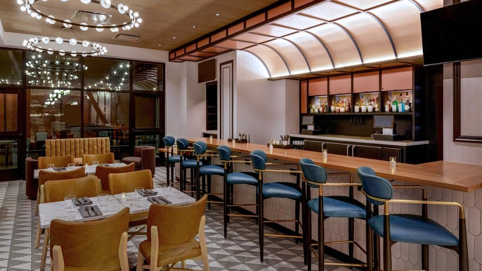 Restaurante upscale casual con barra moderna y asientos iluminados.